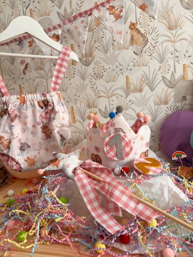 Conjunto de ropa de bebé con estampado, corona decorativa y confeti de colores.